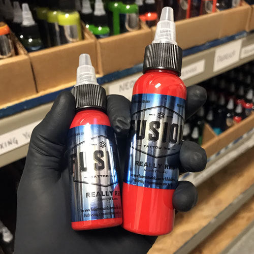 Fusion Ink Tattoo Ink Really Red 1 and 2 Ounce Ink Bottles in a gloved hand