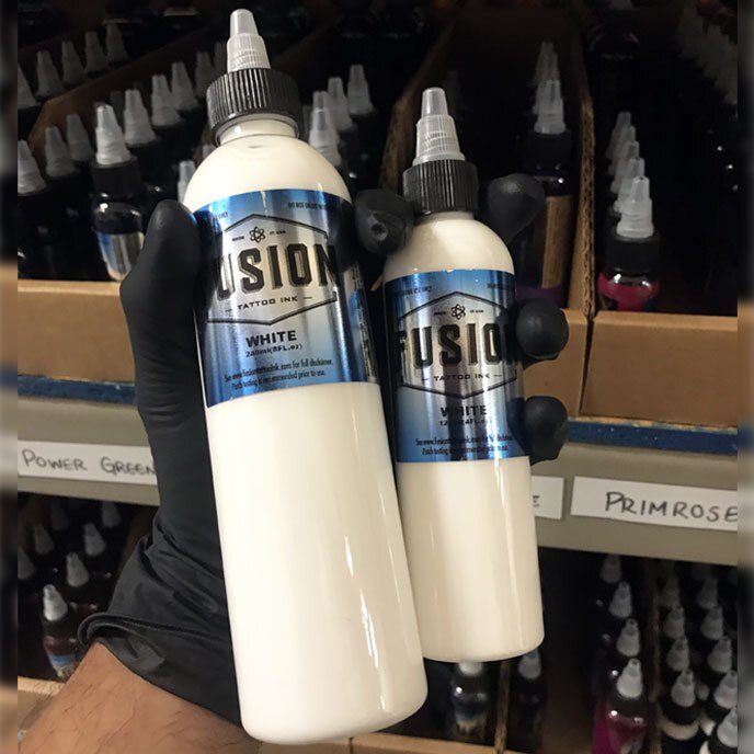 Fusion Ink Tattoo Ink White in 8 Ounce and 4 Ounce Bottles being held by a gloved hand